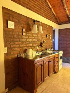 eine Küche mit Spüle und einer Ziegelwand in der Unterkunft Cabañas Atrapasueños in Trevelín