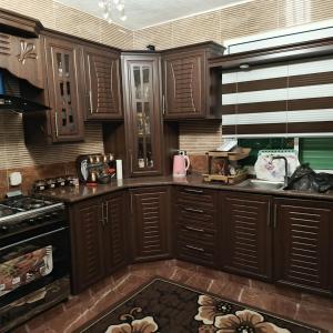 a kitchen with wooden cabinets and a kitchen rug at المناره هاوس in Wadi Musa