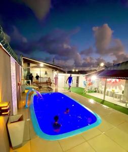two children playing in a swimming pool at night at Tô A Tôa in Touros