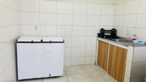 a small kitchen with a white refrigerator and a sink at Tô A Tôa in Touros