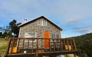 a house with an orange door on a wooden deck at Cabañas Victoria Aucaco in Ancud