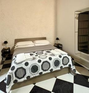 a bedroom with a bed with a black and white comforter at Il Cortiletto di Ortigia in Syracuse