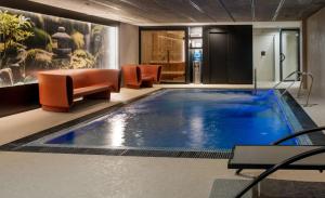 a large swimming pool in a lobby with orange chairs at Hotel Sercotel Plana Onda in Onda