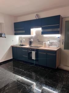 a kitchen with blue cabinets and black marble floors at ZANIK Cozy Haven in Prague