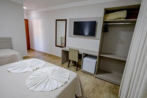 a room with two beds and a desk and a television at Villa de Holanda Parque Hotel in Holambra