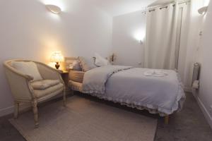 a bedroom with a bed and a chair and a lamp at Maison des Compagnons in Val de Reuil