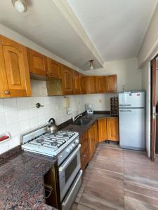 a kitchen with wooden cabinets and a stove and refrigerator at Departamento Torre IV in Comodoro Rivadavia