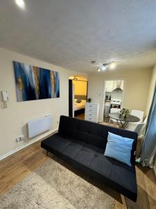 a living room with a black couch and a table at Tranquil 1BD in Edmonton in Ponders End +6 photos