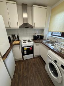 a small kitchen with a stove and a washer at Tranquil 1BD in Edmonton in Ponders End