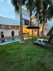 a resort with a pool and palm trees and an umbrella at Oasis TIFNIT Villa with Pool View No vis A vis in Draïd