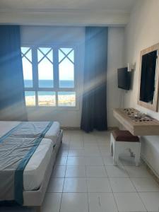 a bedroom with a bed and a desk and a window at Hotel Mezri in Monastir