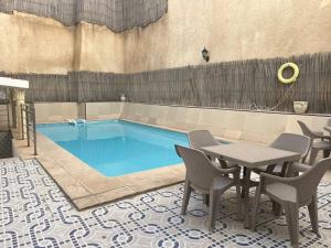 a swimming pool with a table and chairs next to it at Hotel Mezri in Monastir