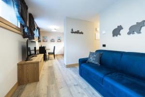 a living room with a blue couch and a tv at Chalet Boscopiano in Valdidentro