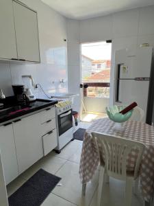 a small white kitchen with a table and a window at Apto Ninho Sereno em ilheus in Ilhéus