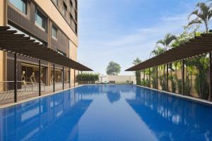 a swimming pool in front of a building at Le Meridien, Surat in Surat