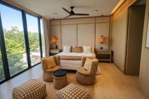 a bedroom with a bed and chairs and a large window at Luxury Villa in Corasol 4BR Private Pool in Playa del Carmen