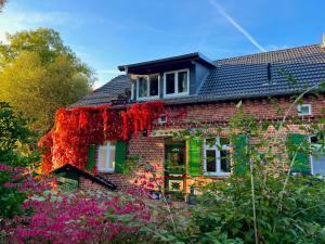 a brick house with red ivy on the side of it at Elbferienhaus Lenzerwische - gemeinsames Urlauben an der Elbe mit privaten Badesee - alles inklusive in Lenzerwische