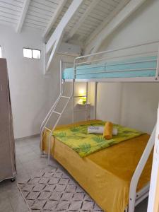 a bedroom with a bunk bed with a yellow bedspread at Haut de villa " JODI " in Sainte-Rose +3 photos