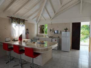 a kitchen with a large island with red chairs at Haut de villa " JODI " in Sainte-Rose