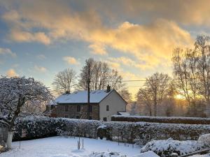 a house in the snow with the sun in the background at Plumes et Pinceaux in Redu
