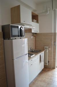 a kitchen with a white refrigerator and a microwave at Cologno Centro Apartment in Cologno Monzese