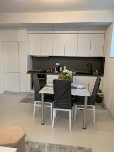 a kitchen with a table and chairs and white cabinets at Aura in Kumanovo +16 photos