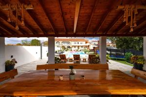 a patio with a wooden table and chairs under a roof at My Dalmatia - Apartment Neda with shared pool in Galovac