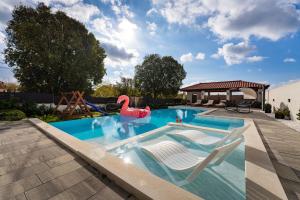 a swimming pool with a swan and two chairs in it at My Dalmatia - Apartment M&N with shared pool in Galovac
