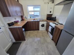 a kitchen with wooden cabinets and a washer and dryer at Magic Stays! in Halton