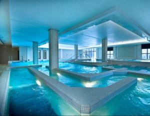 a large pool with blue water in a building at Apt au calme, 2-3 chambres, Sauna, 2 parkings, bus sur place in Montévrain