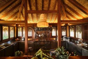 a kitchen with a large wooden ceiling with a chandelier at Villa Heremoana in Maharepa