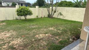 a yard with two trees in front of a fence at Casa do Igra in Torres +1 photo