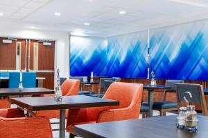 a room with tables and chairs and a painting on the wall at Holiday Inn Express Hotel & Suites Memphis/Germantown by IHG in Memphis