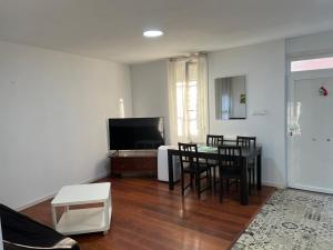 a living room with a table and chairs and a television at Habitaciones Carmen in Rubí