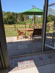 a patio with a picnic table and an umbrella at The Roost at The Gables Farm in Poynton