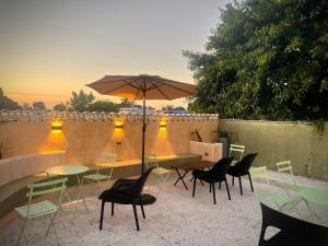 eine Terrasse mit Tischen, Stühlen und einem Sonnenschirm in der Unterkunft Cien Sueños Hotel Boutique in Mérida