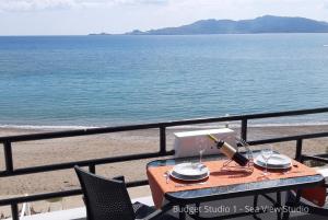 a table on a balcony overlooking the beach at Budget Studios Haraki in Haraki