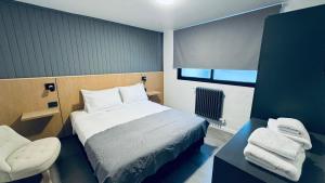 a small bedroom with a bed and a chair at Hotel Manquehue in Esquel