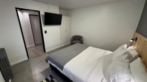 a bedroom with a bed and a flat screen tv at Hotel Manquehue in Esquel