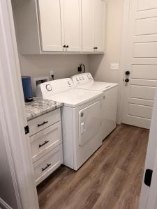 a kitchen with white cabinets and a washer and dryer at Wanderlust House in Shreveport +30 photos