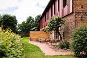 a patio with a table and benches next to a building at Gut-Royum-Strohlager in Brodersby +10 photos