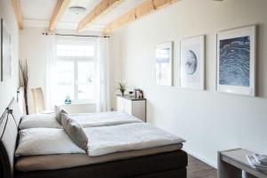 a bedroom with a bed with white walls and a window at Gut-Royum-Haferkiste in Brodersby