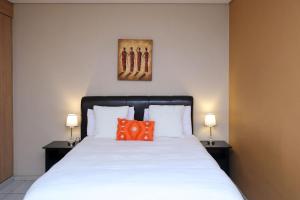 a bedroom with a white bed with an orange pillow at The Orange Corner II in Johannesburg