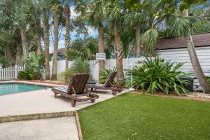 two lounge chairs next to a swimming pool with palm trees at Be A Nomad - Pool Access Studio Apartment - Jacksonville Beach Couples in Jacksonville Beach