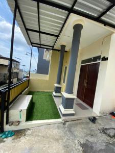 a house with a porch with a green floor and a door at Locita Villa in Batu +6 photos