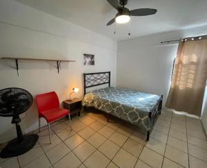 a bedroom with a bed and a red chair at Casa del Estadio in Guadalajara