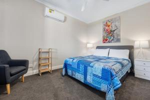 a bedroom with a bed and a chair at Cottage on Carson in Geraldton