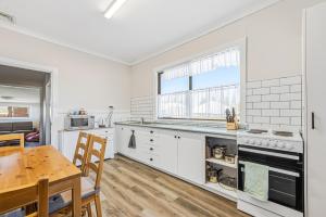 a kitchen with white cabinets and a wooden table at Cottage on Carson in Geraldton +12 photos