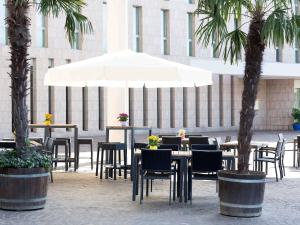a patio with tables and chairs and a white umbrella at Novotel Freiburg am Konzerthaus in Freiburg im Breisgau