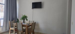 a dining room table with chairs and a television on a wall at Bem te vi in Niterói